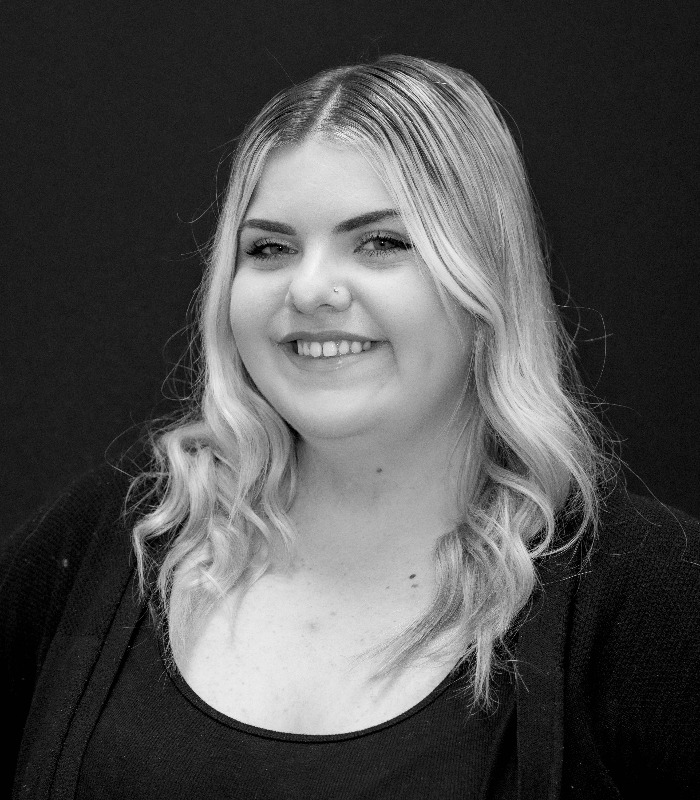 Meet Our Team - Professional and Welcoming Group at a Conference Table Faces the Camera, Team Leader Sitting on the Table with Arms Folded