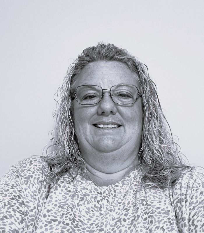 Meet Our Team - Professional and Welcoming Group at a Conference Table Faces the Camera, Team Leader Sitting on the Table with Arms Folded